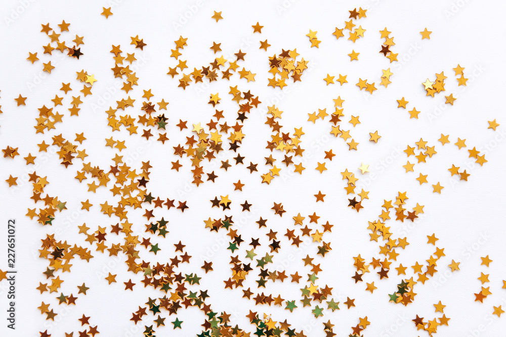 Festive golden stars of confetti on a white background.