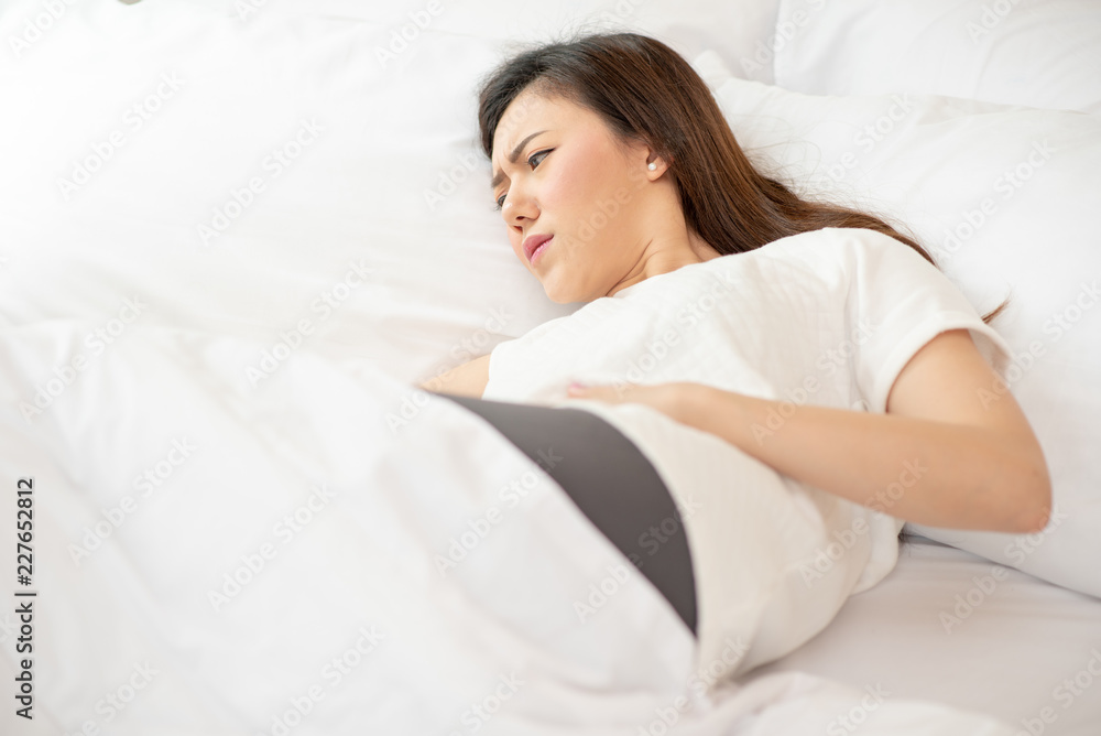 Asian woman stomachache on the white bed, feel pain Asian woman stomachache on the white bed, feel pain
