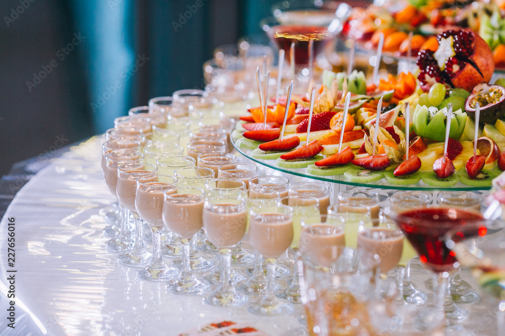 Candy bar with a lot of cookies and fruits during the wedding. chocolate fountain and wedding cake. Coktails and drink at the table