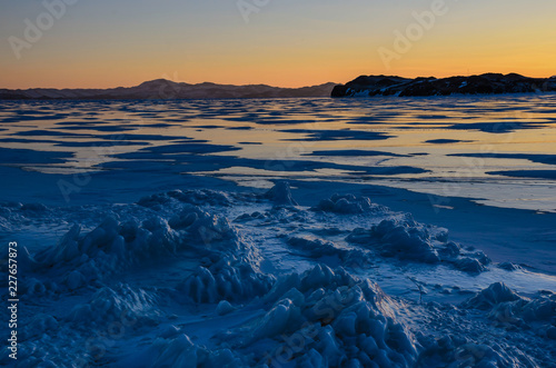 View of the ice and the rising sun over the mountains, lake Baikal