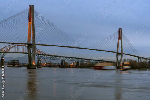 Bridge Over Fraser River with Motion Blurred Tug Pulling Barge in New Westminster British Columbia © Todd