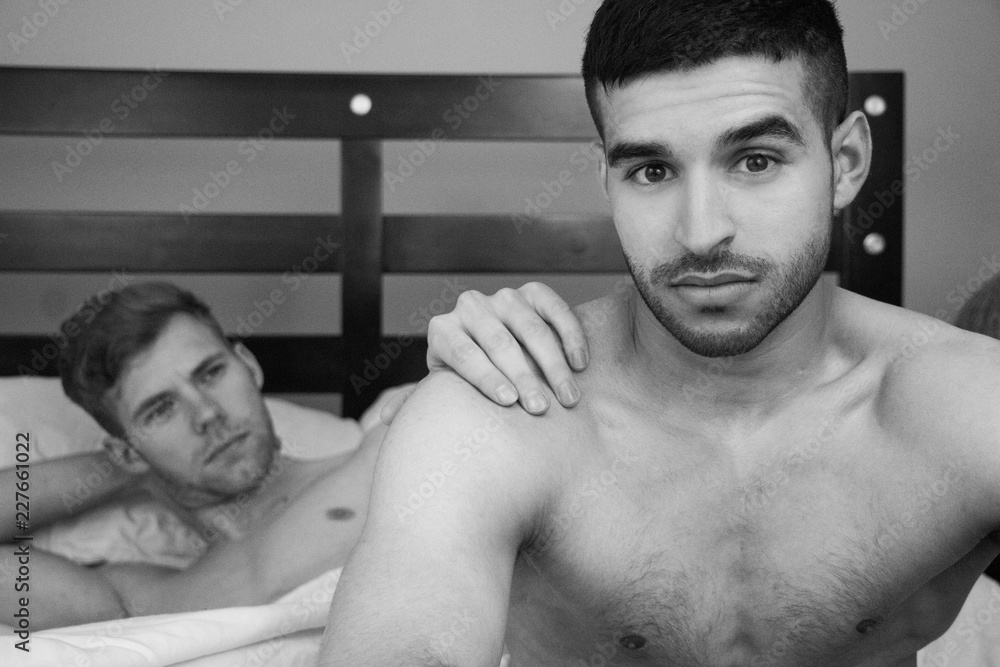 Gay lovers sitting in bed, one of them looks at camera as other looks at  his partner foto de Stock | Adobe Stock