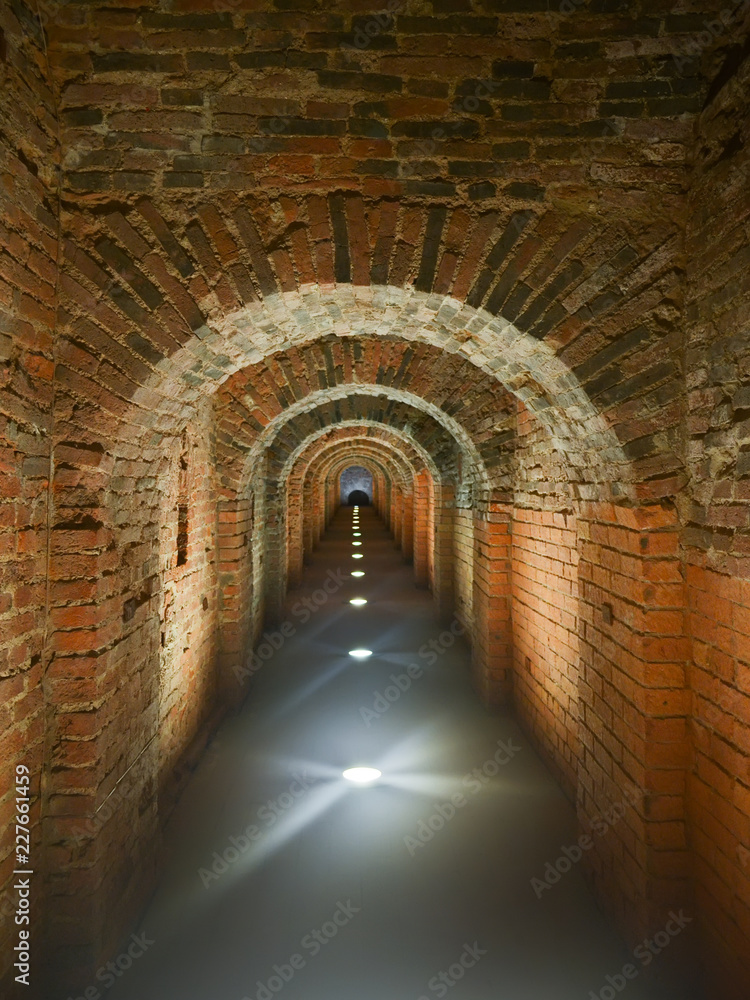Dark brick long mystical arched corridor illuminated in the floor