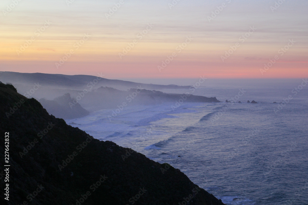 Evening pink sunset over the ocean and rocky coastline of big sur