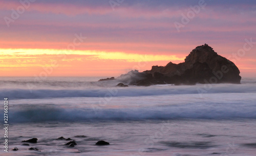 Sunset behind huge stone formations on Pfeiffer Beach in Big Sur, California