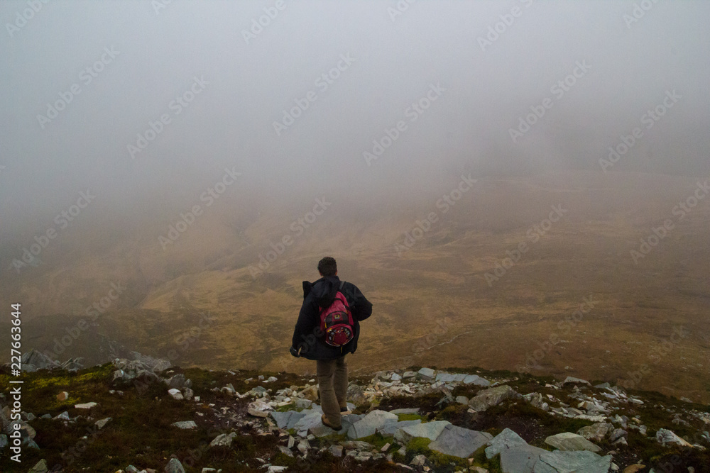 Man hiking in foggy moody Connemara national park in Ireland