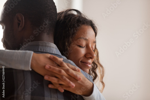 Close up young black american wife embracing husband. Portrait of woman with closed eyes, man rear view. Attractive affectionate couple in love, romantic relationship support and gratefulness concept photo