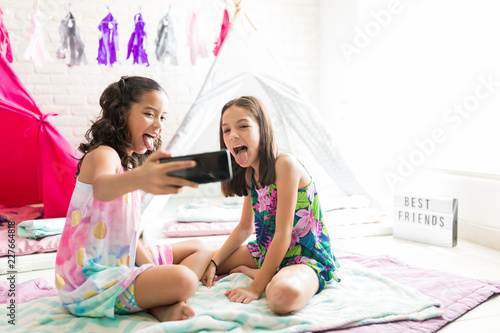 Girls Sticking Out Tongue While Taking Selfie On Smartphone
