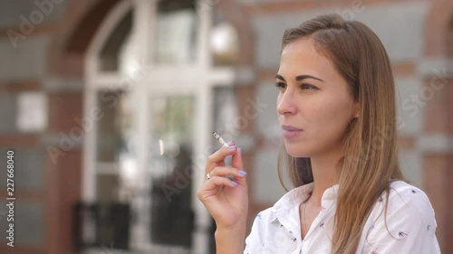 Young beautiful woman smokes on the street. 4k. slow motion