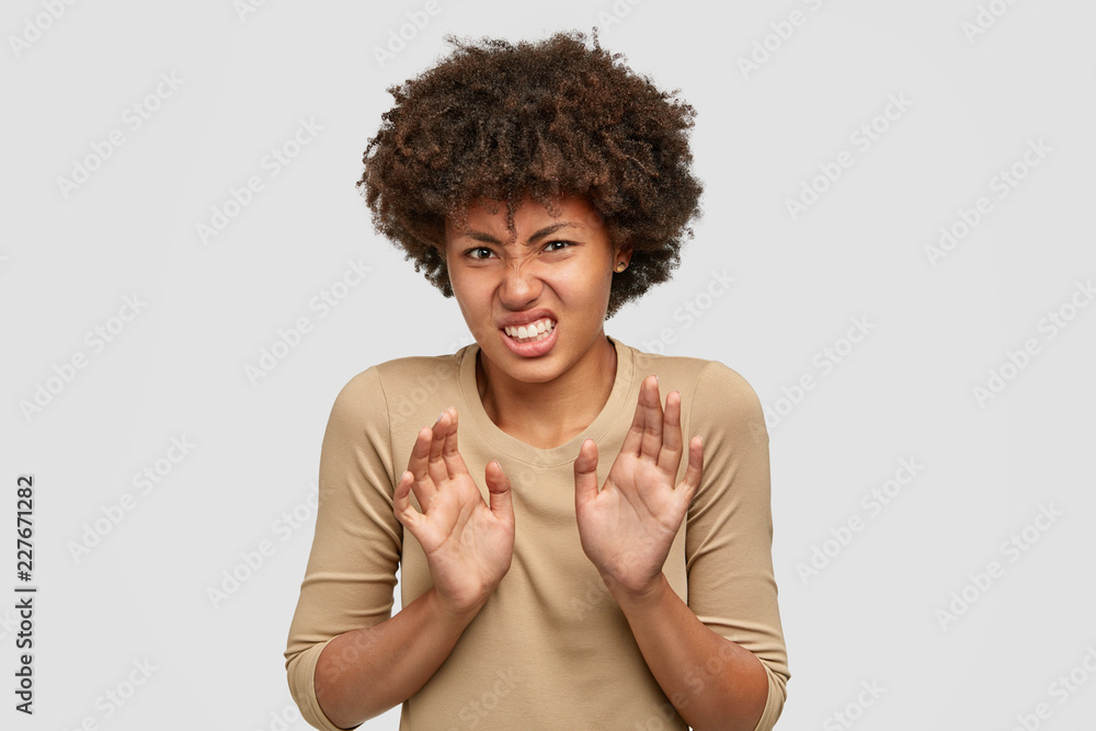 Dont suggest it for me! Bothered intense dissatisfied dark skinned girl frowns face in discontent, feels aversion, pulls hands in refusal gesture, clenches teeth, dressed casually, isolated on white Dont suggest it for me! Bothered intense dissatisfied dark skinned girl frowns face in discontent, feels aversion, pulls hands in refusal gesture, clenches teeth, dressed casually, isolated on white