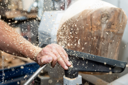 carpenter forms rotating wood with turnery and flying timber saw dust