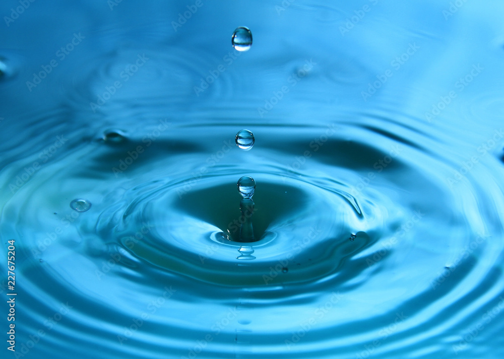 A drop of water is falling. Abstract blue background. A drop of water is falling. Abstract blue background.