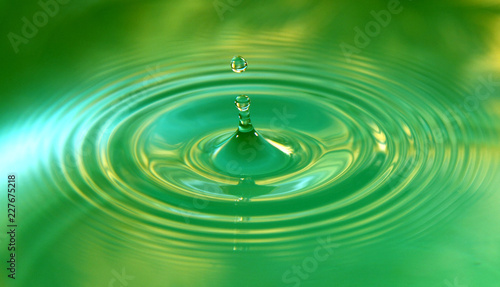 A drop of water is falling. Abstract green background.