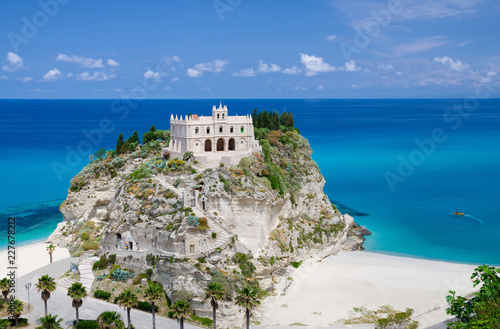 Monastery Sanctuary church of Santa Maria dell Isola on top of rock Tyrrhenian Sea and green palm trees, blue sky white clouds in summer clear day, Tropea town, Vibo Valentia, Calabria, Southern Italy photo