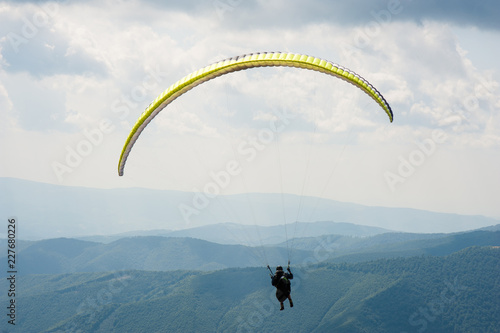 One paraglider fly over a mountain valley on a sunny summer day. Paragliding in the Carpathians in the summer.