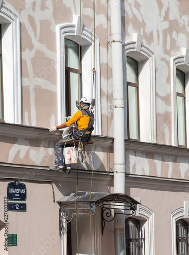 Man is doing old historical building restoration in downtown hunging on the saf