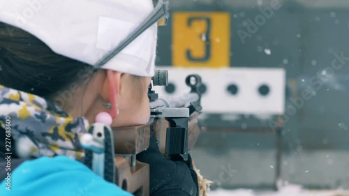 Biathlon athlete shooting, back view.