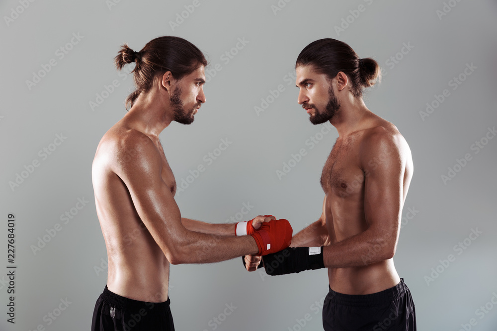 Portrait of a two confident muscular shirtless twin brothers
