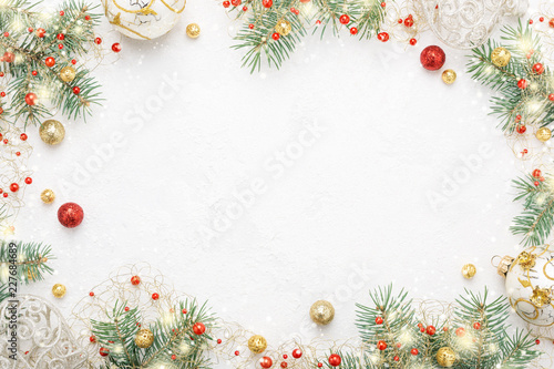 Christmas frame of spruce, red and gold decorations on white background. Copy space. New Year lights. Flat lay.