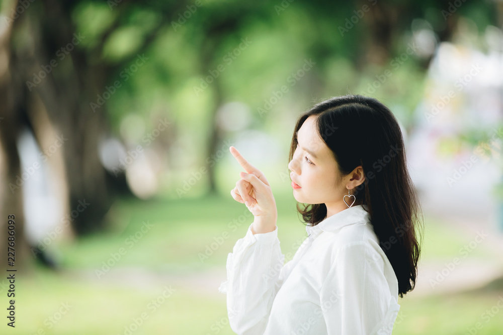 portrait of asian girl with white shirt and skirt pointing in outdoor nature vintage film style