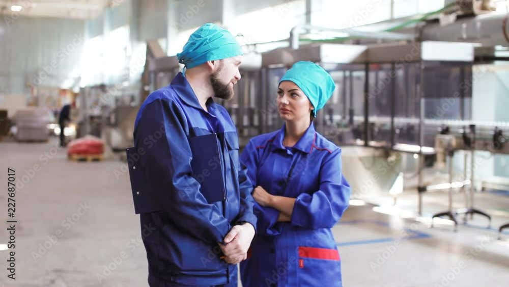 two workers talking in factory