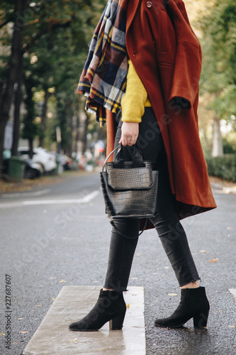 street style, attractive woman wearing a brown oversized coat,black jeans, ankle boots and a croc effect tote bag. fashion outfit perfect for sunny autumn.