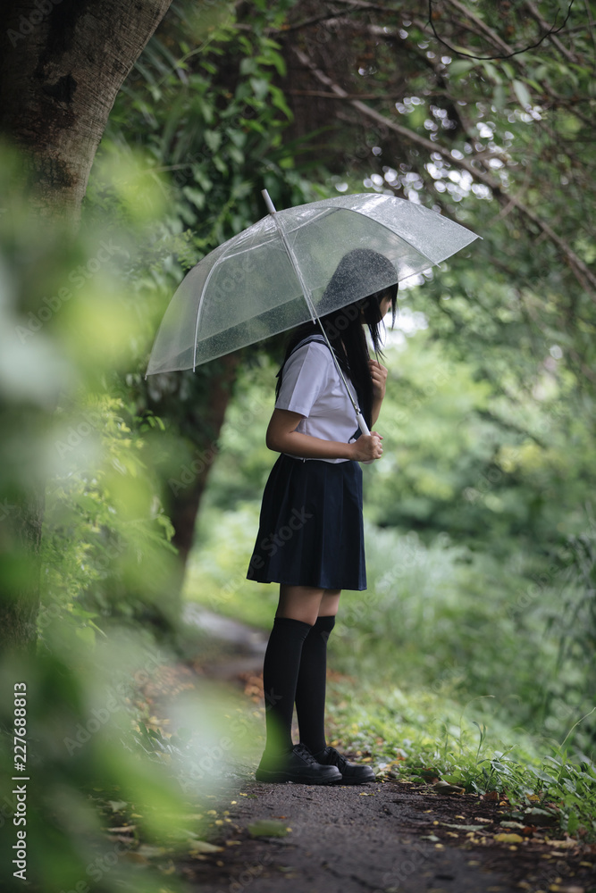 Portrait of Asian school girl walking with umbrella at nature walkway on raining Portrait of Asian school girl walking with umbrella at nature walkway on raining
