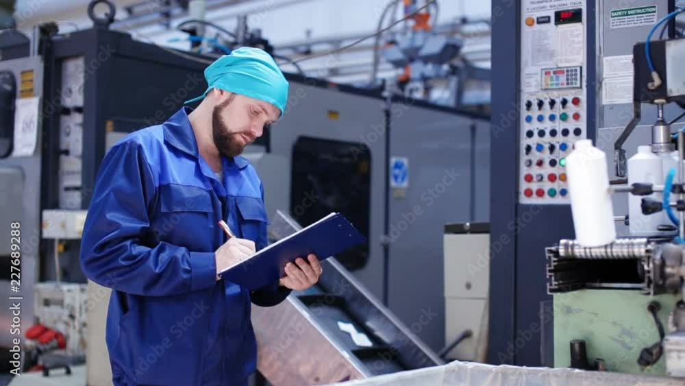 Worker with clipboard near machinery in factory Worker with clipboard near machinery in factory