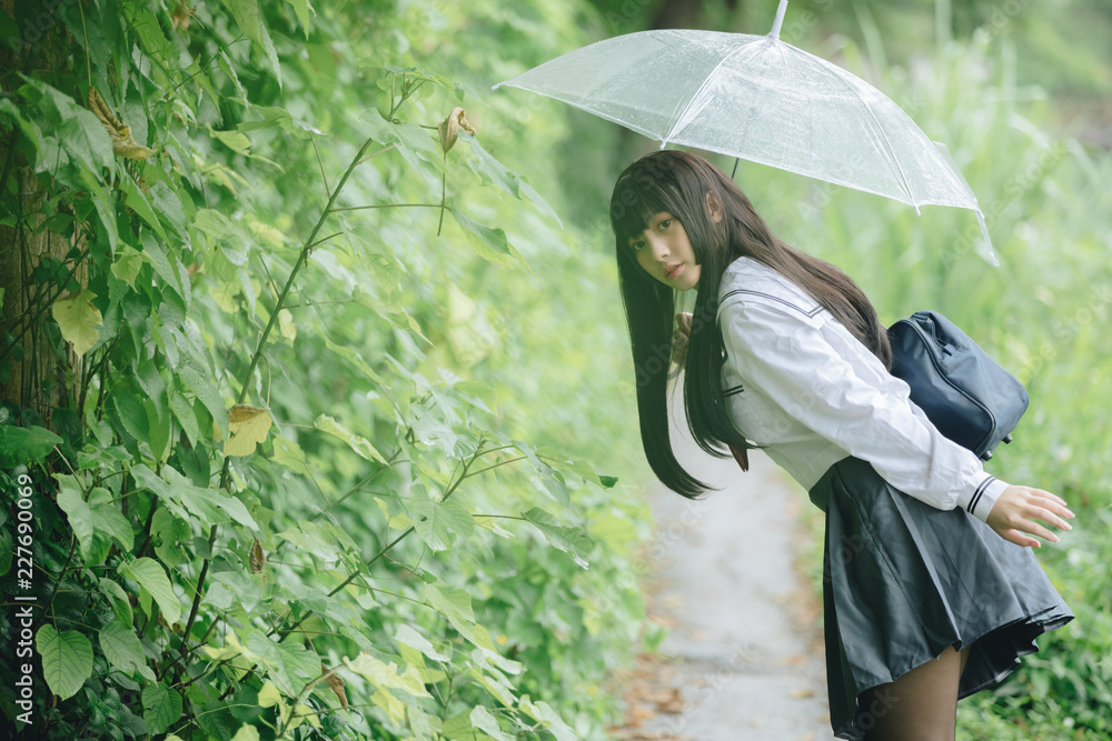 Portrait of Asian school girl walking with umbrella at nature walkway on  raining foto de Stock | Adobe Stock