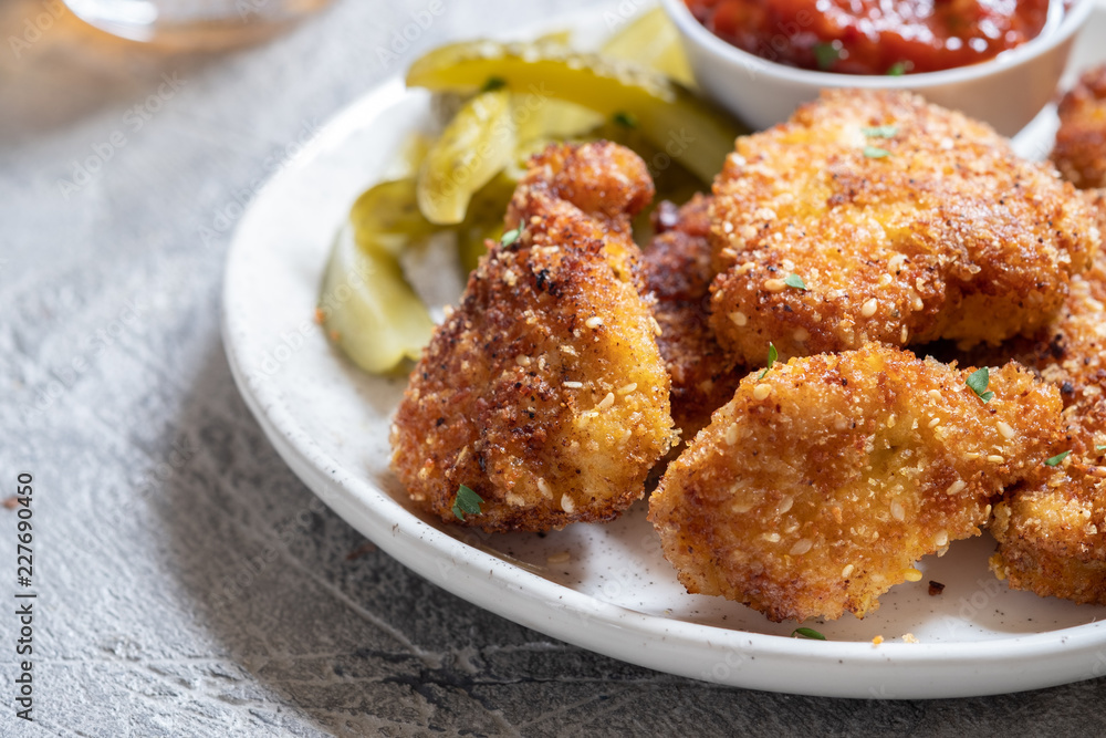 Fried crispy chicken nuggets with ketchup and pickles