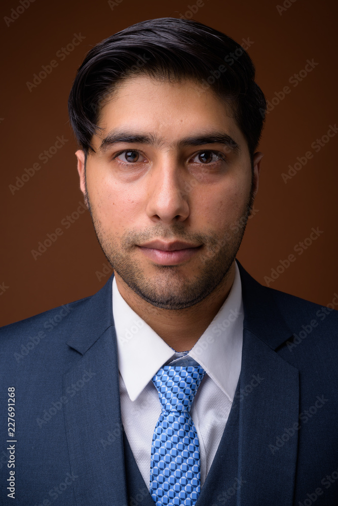Young handsome Iranian businessman against brown background Young handsome Iranian businessman against brown background