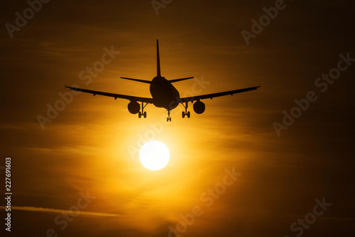 Silhouette of an air plane near to the sun with beautiful red clouds in background