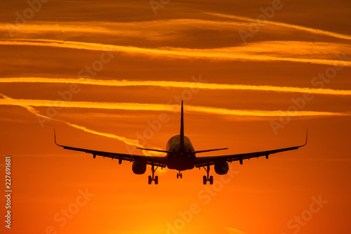Airplane prepare for landing at sunset with beautiful red sky in background
