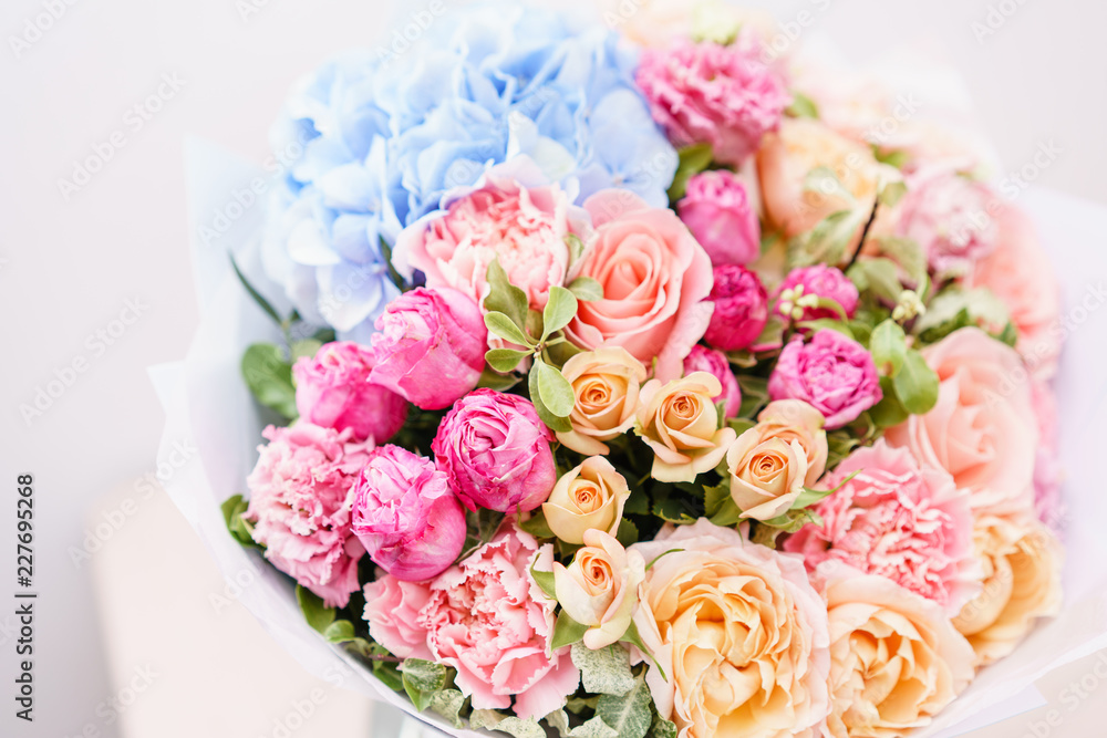 beautiful spring bouquet. flowers arrangement with various of colors in glass vase on pink table. bright room, white wall. beautiful spring bouquet. flowers arrangement with various of colors in glass vase on pink table. bright room, white wall.