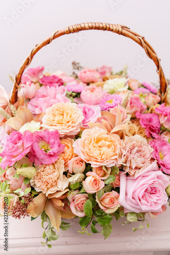 flowers arrangement with various of colors in wicker basket on pink table. beautiful spring bouquet. bright room  white wall. copy space