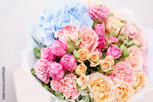 beautiful spring bouquet. flowers arrangement with various of colors in glass vase on pink table. bright room, white wall.