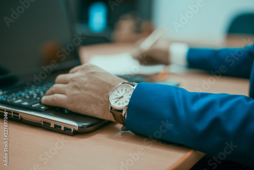 a man in a sui ussing a laptop, a businessman at a laptop (brown tonted) photo