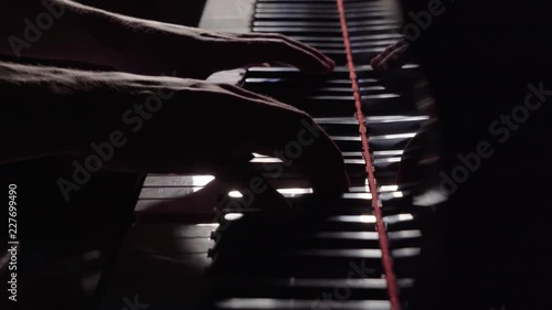 Close Up Slender Hands Approach Piano and Play Slowly in Dark Intense Lighting photo