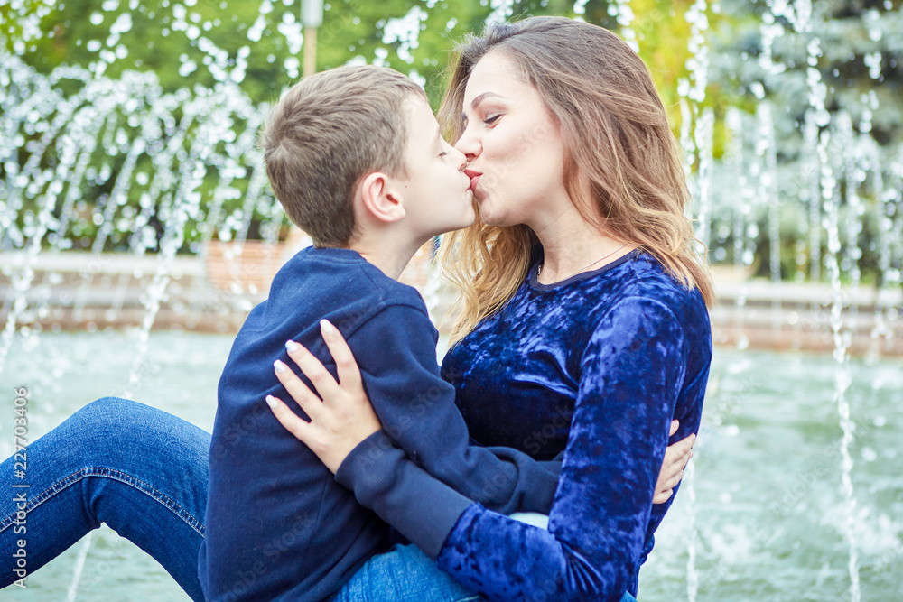 Happy beautiful mother and son enjoying near the fountain Happy beautiful mother and son enjoying near the fountain