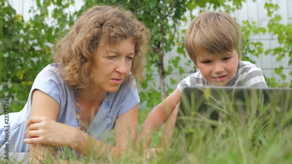 Boy with teacher background. Mother and child. lying on grass. Alternative education. Alternative schooling. Studying outdoors. Home schooling. Teacher and pupil. Outdoor activities. Boy with teacher background. Mother and child. lying on grass. Alternative education. Alternative schooling. Studying outdoors. Home schooling. Teacher and pupil. Outdoor activities.