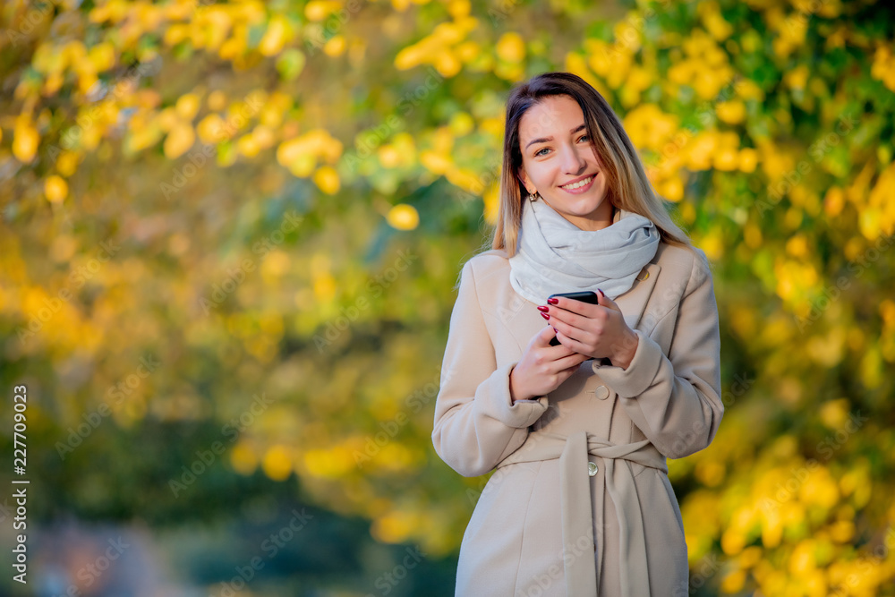 Young girl with mobile phone on autumn season street Young girl with mobile phone on autumn season street