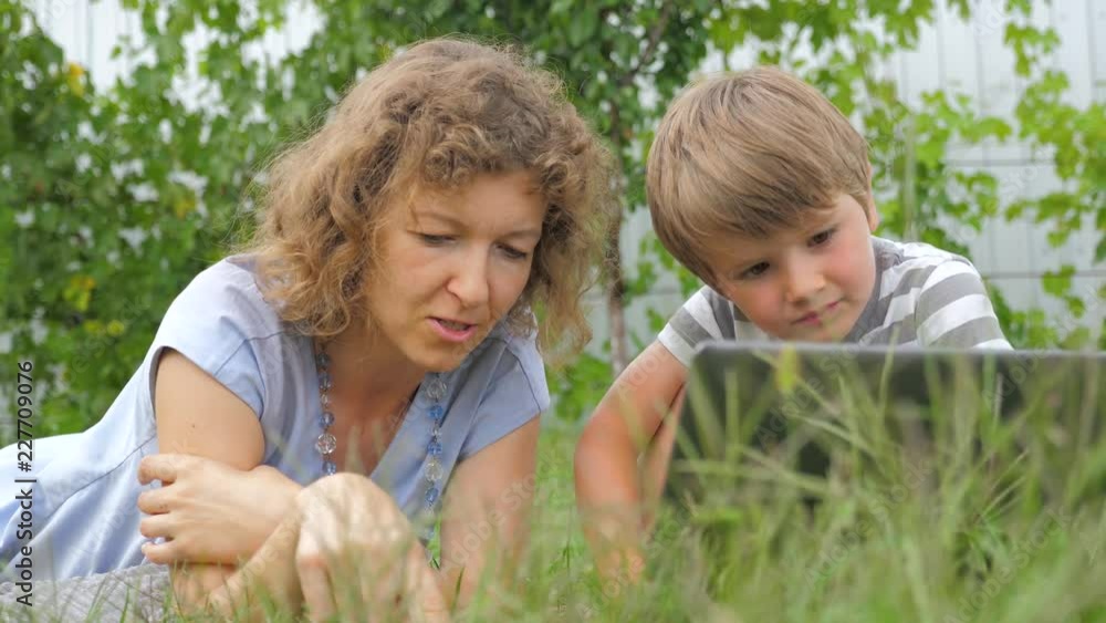 Boy with teacher background. Mother and child. lying on grass. Alternative education. Alternative schooling. Studying outdoors. Home schooling. Teacher and pupil. Outdoor activities. Boy with teacher background. Mother and child. lying on grass. Alternative education. Alternative schooling. Studying outdoors. Home schooling. Teacher and pupil. Outdoor activities.