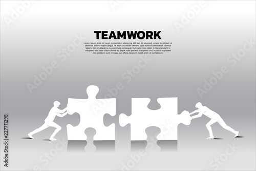 Silhouette of two businessman pushing two jigsaw pieces puzzle. concept of business teamwork.