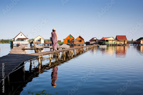 woman walking on the planks at floating village on lake Bokod, Hungary