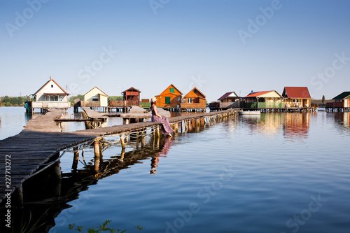 woman walking on the planks at floating village on lake Bokod  Hungary