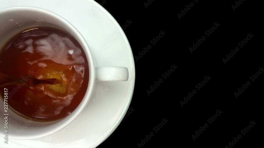 Coffee being poured slowly into a cup on a saucer viewed from above against a pure black background Coffee being poured slowly into a cup on a saucer viewed from above against a pure black background
