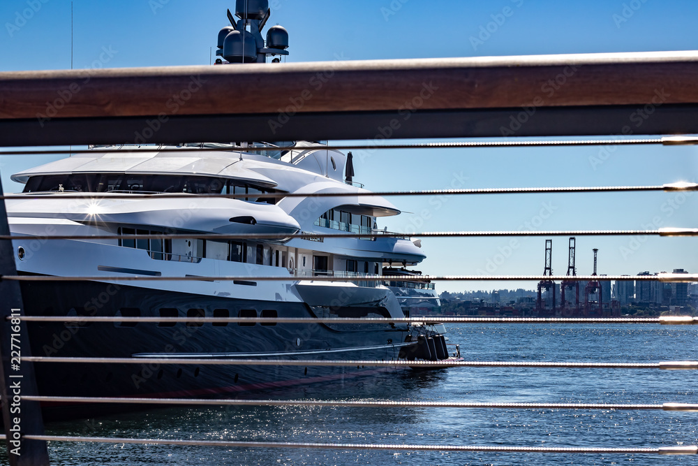 Looking through a guardrail at a docked yacht on a sunny day.