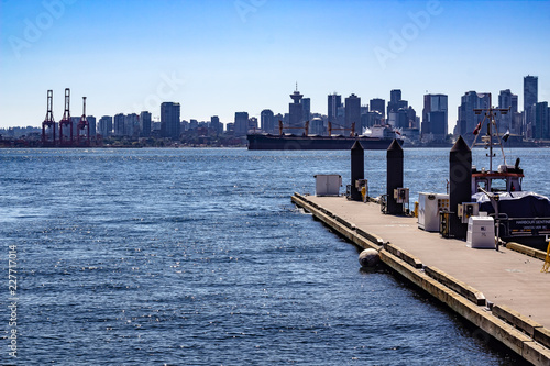 Obraz na płótnie Looking off the dock at Lonsdale Quay, Vancouver British Columbia on a sunny day at a major shipping lane. Barges, tugs and city skyline w salonie