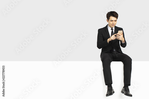  businessman watching smart phone and sitting on blank panel © Tom Wang