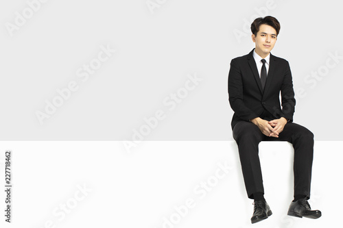 Young business man sitting on blank panel © Tom Wang